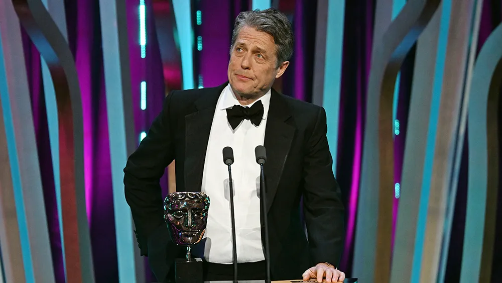 Hugh Grant Injects ‘Wonka’ Oompa Loompa Flair While Presenting Best Director BAFTA Award: ‘Most of These Films Were Frankly Too Long’